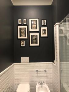 a bathroom with a toilet and framed pictures on the wall at Villa Gotti Charming Rooms in Bologna +59 photos
