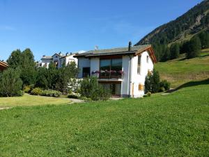 ein Haus auf einem Hügel mit grünem Rasen in der Unterkunft Chesa Ovelin in Pontresina