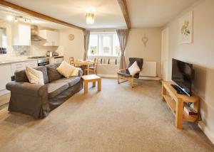 a living room with a couch and a television at Host & Stay - Cosy Cottage in Emley