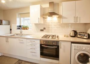 een keuken met witte kasten, een fornuis en een wastafel bij Host & Stay - Cosy Cottage in Emley