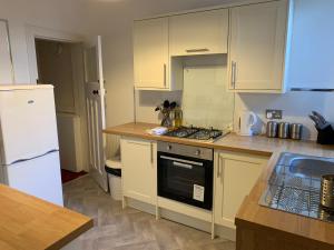 a kitchen with white cabinets and a stove top oven at Charles's Street in Largs