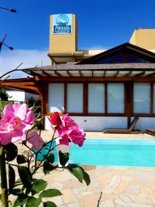 a house with a swimming pool and pink flowers at Pousada Nascer do Sol in Penha