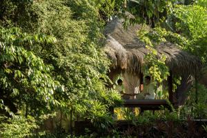 two people sitting on a bench in a hut at Four Seasons Resort Langkawi in Tanjung Rhu