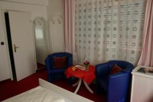 a bedroom with two blue chairs and a red table at Hotel Café Talblick in Vielbrunn
