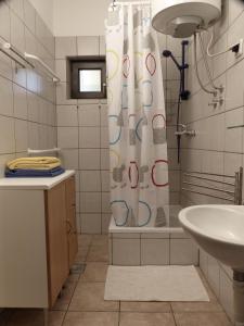 a bathroom with a shower curtain and a sink at Apartments Different Colours in Šilo