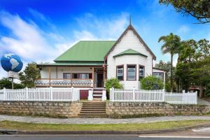 Casa blanca con techo verde y valla en Port Macquarie Backpackers, en Port Macquarie