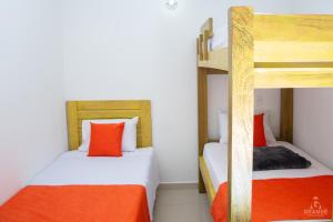 ヘリコにあるHotel Madre Laura Jericóのオレンジと白を基調としたドミトリールームの二段ベッド2台