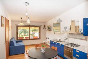 cocina y sala de estar con mesa y silla azul en Résidence Villa Smeralda, en Telti