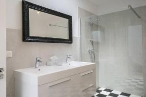 a white bathroom with a sink and a shower at B&B Valkenbos in The Hague