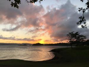 una puesta de sol sobre un cuerpo de agua con un árbol en Arenal Garden Lodge, en El Castillo de La Fortuna