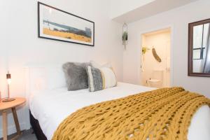 ein Schlafzimmer mit einem weißen Bett und einem Tisch in der Unterkunft Anzac North Loft - 4 Bedrooms & 2 Free Car Parks in Auckland