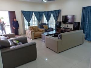 a living room with couches and a tv at PD Swimming Pool Homestay in Port Dickson