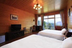 una camera da letto con due letti e una TV a schermo piatto di Yun Meng Xianjing Homestay a Ren'ai