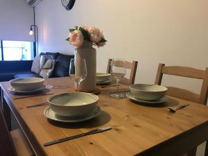 a wooden table with plates and flowers in a vase at New Luxurious Skyview 2Bedroom Apartment Liverpool in Liverpool