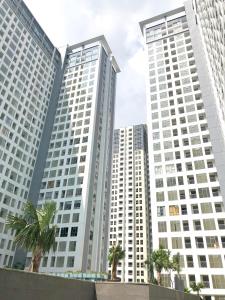 three tall buildings with palm trees in front of them at M-Town Residence Gading Serpong by Taslim Property in Tangerang
