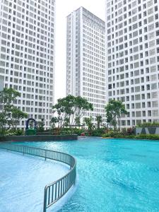 a large pool of water with two tall buildings at M-Town Residence Gading Serpong by Taslim Property in Tangerang
