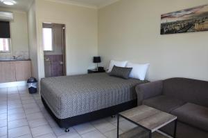 um quarto com uma cama e um sofá em Tumut Apartments em Tumut