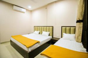 two beds in a small room with yellow and white at Namastay Welcome Home in Ratlām