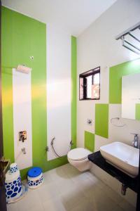 a green and white bathroom with a toilet and a sink at Namastay welcome home - Abu Road in Ābu Road