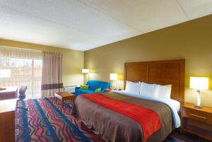 a hotel room with a bed and a chair at Baymont by Wyndham Bonita Springs in Bonita Springs