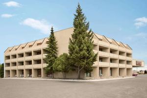 a large building with two trees in front of it at Travelodge Hotel by Wyndham Kingston Lasalle in Kingston