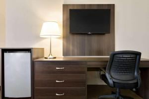a room with a desk with a chair and a television at Travelodge Hotel by Wyndham Kingston Lasalle in Kingston