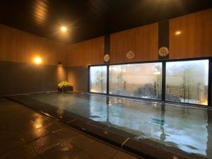 a swimming pool in a building with a large window at Hotel Route-Inn Tsuchiura in Tsuchiura