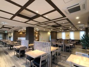 Hotel Route-Inn Tsuchiura في تسوشيورا: غرفة طعام مع طاولات وكراسي خشبية