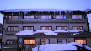 un edificio con carámbanos en el techo con nieve en Tabist Kazeyuki, en Takayama