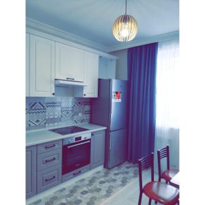 a kitchen with white cabinets and a stove top oven at Best apartment on Sauran Towers in Astana