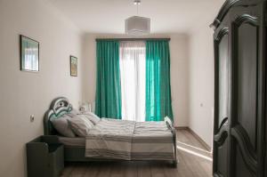 - une chambre avec un lit doté d'un rideau vert et d'une fenêtre dans l'établissement Apartment Near Church, à Tbilissi