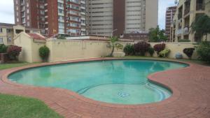 a large swimming pool with a brick walkway around it at Durban Accommodation 118 Summersands in Durban