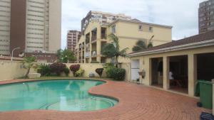 a swimming pool with a brick walkway next to a building at Durban Accommodation 118 Summersands in Durban