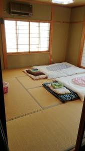 two beds in a room with towels on the floor at Nobu Guest House in Kanayama