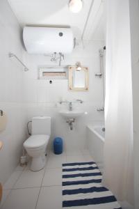 a white bathroom with a toilet and a sink at Vila Ramybe in Palanga