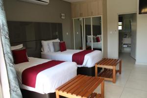 a hotel room with two beds and a bench at Sandpiper Villas Chobe in Kasane