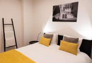 a bedroom with a white bed with yellow pillows at House Forelle Gent in Ghent