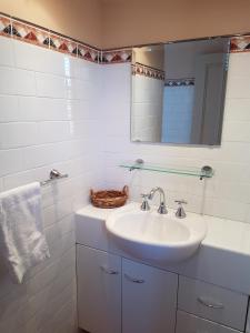 Baño blanco con lavabo y espejo en Highlands Hotel, en Mittagong