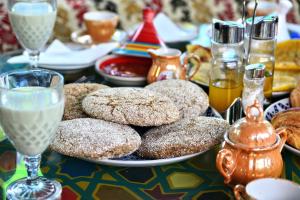 a table with a plate of donuts and glasses of milk at Riad Razoli Sidi Fateh in Rabat