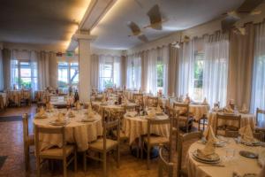 una sala da pranzo con tavoli, sedie e finestre di Giovanna Regina Hotel a Gabicce Mare