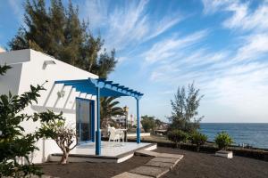 ein weißes Haus mit einem blauen Regenschirm und dem Meer in der Unterkunft Sandos Atlantic Gardens in Playa Blanca