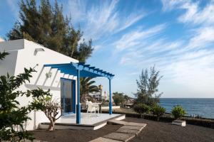 a white house with a blue umbrella and the ocean at Sandos Atlantic Gardens in Playa Blanca