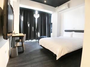 a bedroom with a bed and a desk and a television at Wu Ting Stay in Hualien City