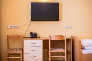 Habitación con escritorio y TV en la pared. en Guesthouse Beno, en Starše