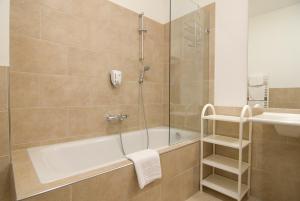 ein Badezimmer mit einer Dusche, einer Badewanne und einem Waschbecken in der Unterkunft Hotel Bräuwirt in Kirchberg in Tirol