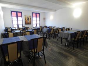 an empty room with tables and chairs and windows at Hôtel Les Comtes de Pardiac in Marciac