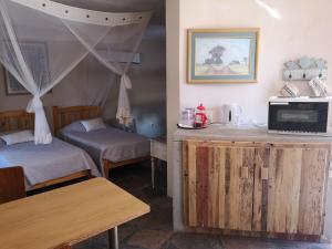 Cette chambre comprend deux lits et un comptoir avec une table. dans l'établissement Terra Rouge Guestfarm & Sonstraal Farmhouse, à Koës