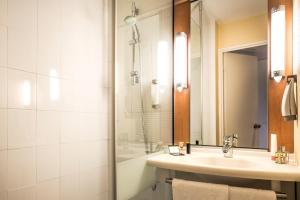 a bathroom with a shower, sink, and mirror at ibis Paris Montmartre 18ème in Paris