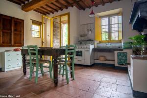 une cuisine avec une table en bois et des chaises vertes dans l'établissement La Casina dei Frati, à Lucques