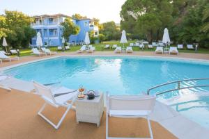 a pool with white chairs and a table and chairs at Mandraki Village Boutique Hotel in Koukounaries